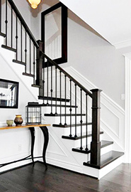 Escalier blanc avec rampe, poteaux, barreaux et marches foncés.