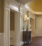 Entrance ways with a dark beige wall with moulding along the entrance and paneling on the bottom along the walls